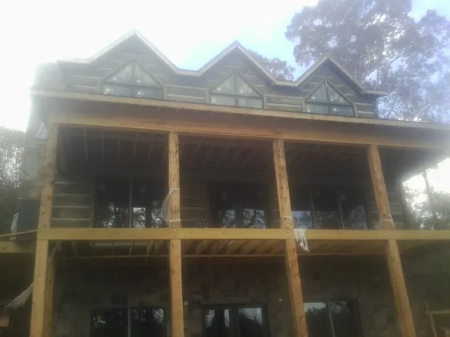Dormers and porch framing on a large log home under construction — Roof Coating work by our crew in Lake Forest