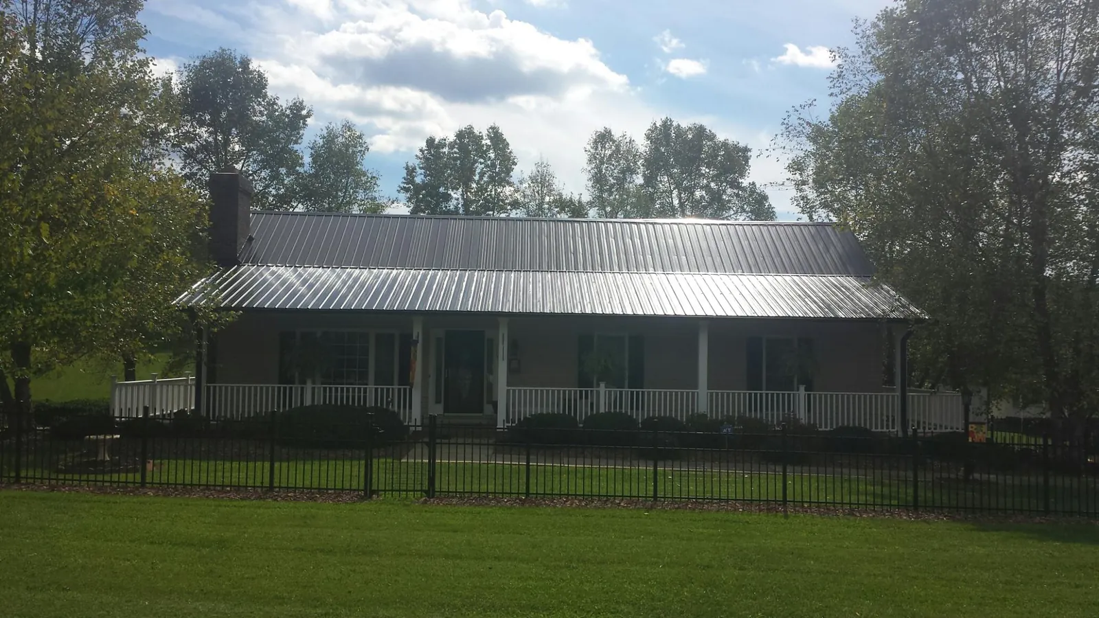 Gray metal roof on a brick ranch with a full width front porch — Gutter Guard Installation work by our crew in Lake Forest
