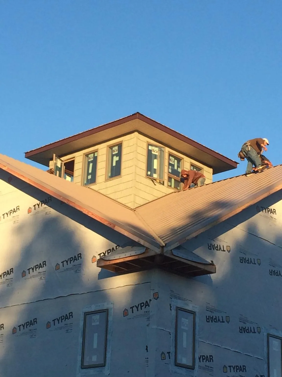 Roofers working around a rooftop cupola on a new metal roof at sunset — Roof Waterproofing in Lake Forest by Roofing Brothers